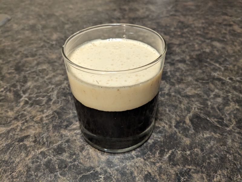Image of a glass filled with coffee and a layer of custard over top, based on Giang's Egg Coffee recipe.
