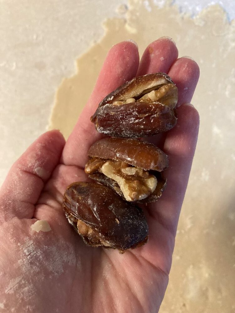 Hand holding dates stuffed with almonds.